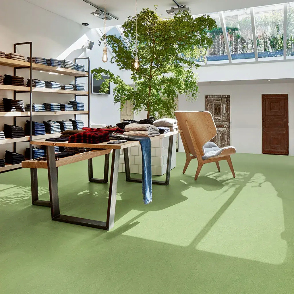 Piso verde en un espacio comercial con mobiliario de madera
