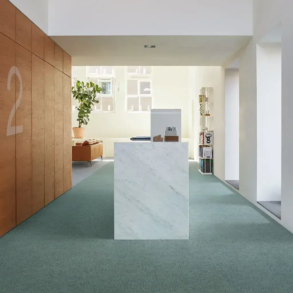 Recepción con mostrador de mármol y alfombra verde
