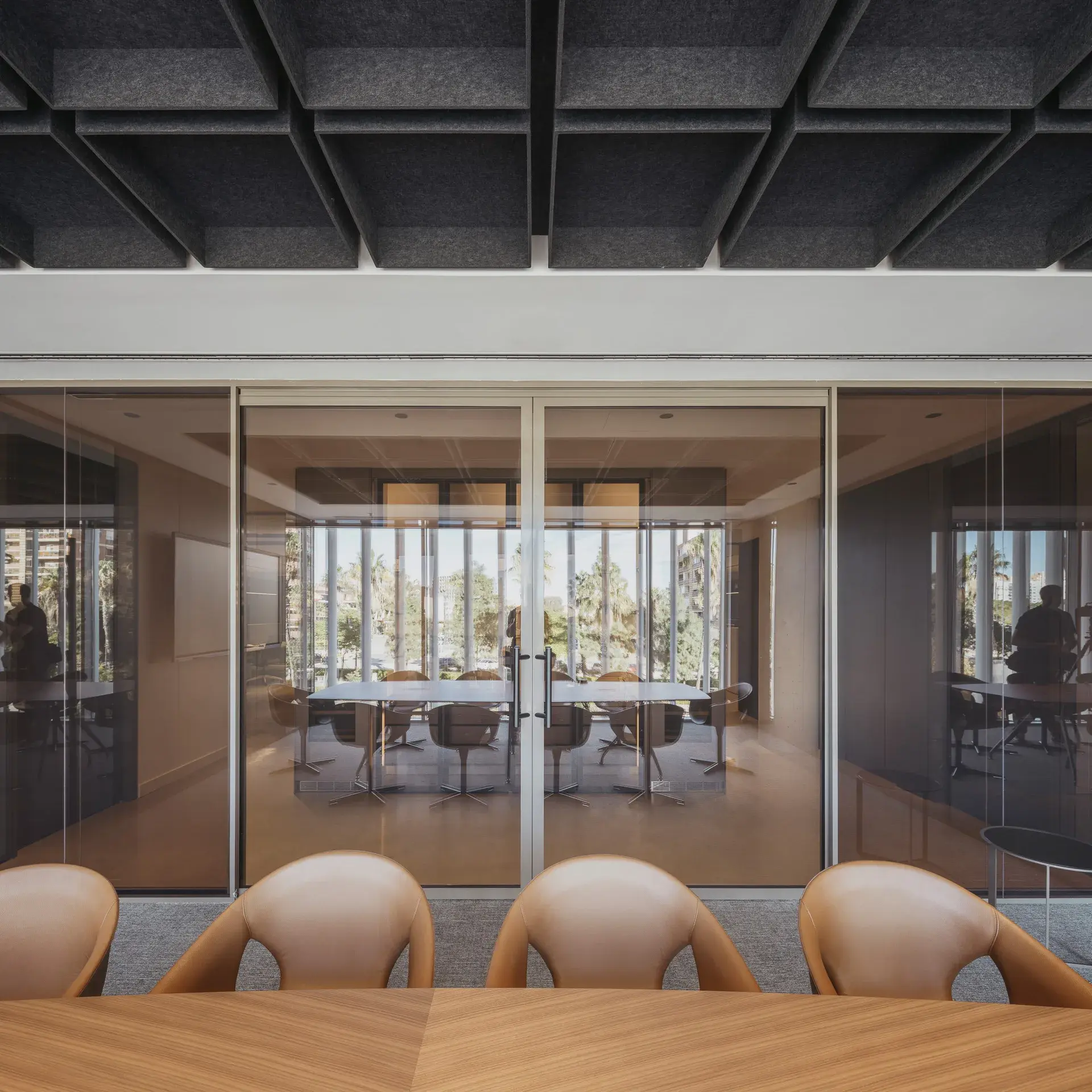 Sala de reuniones con divisiones de vidrio y techo oscuro