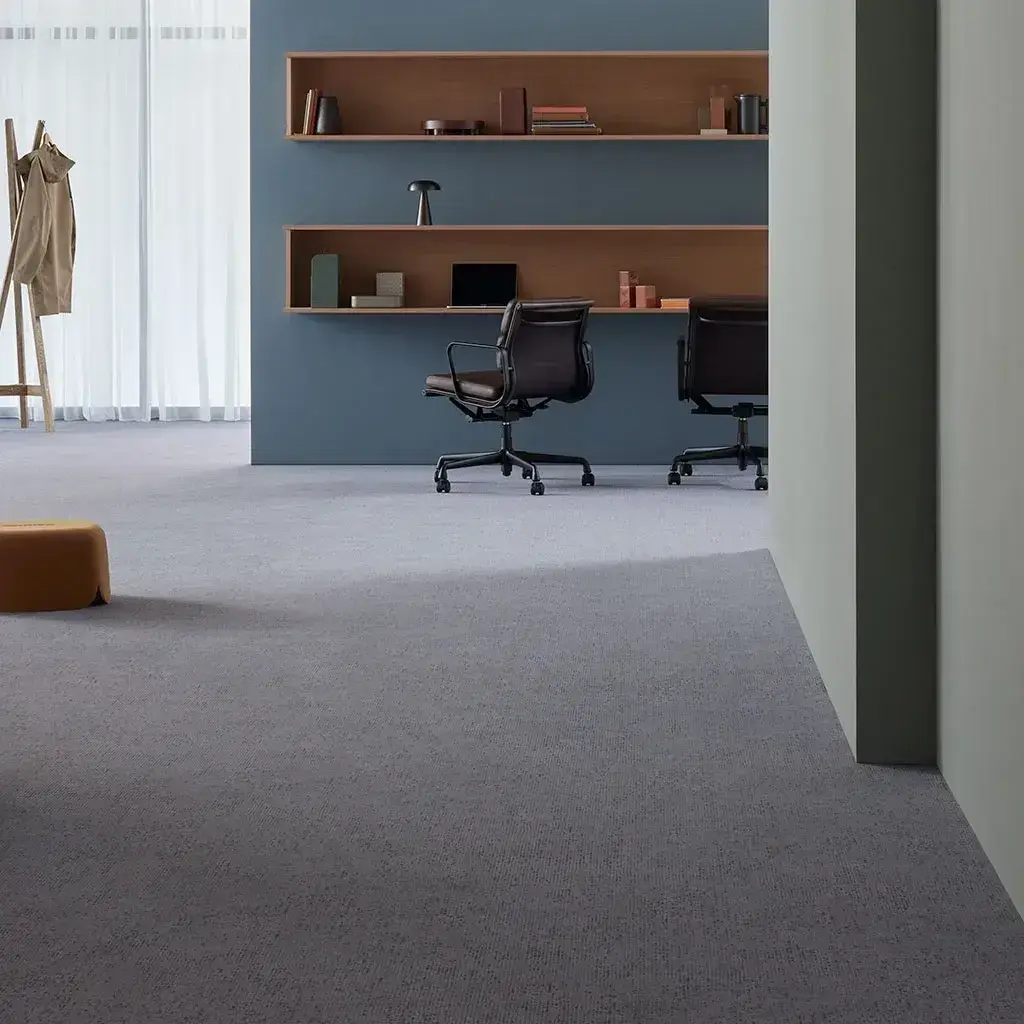 Puesto de trabajo con alfombra gris y estantería de madera
